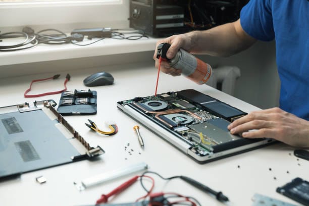 computer maintenance - technician blow out dust from laptop fan
